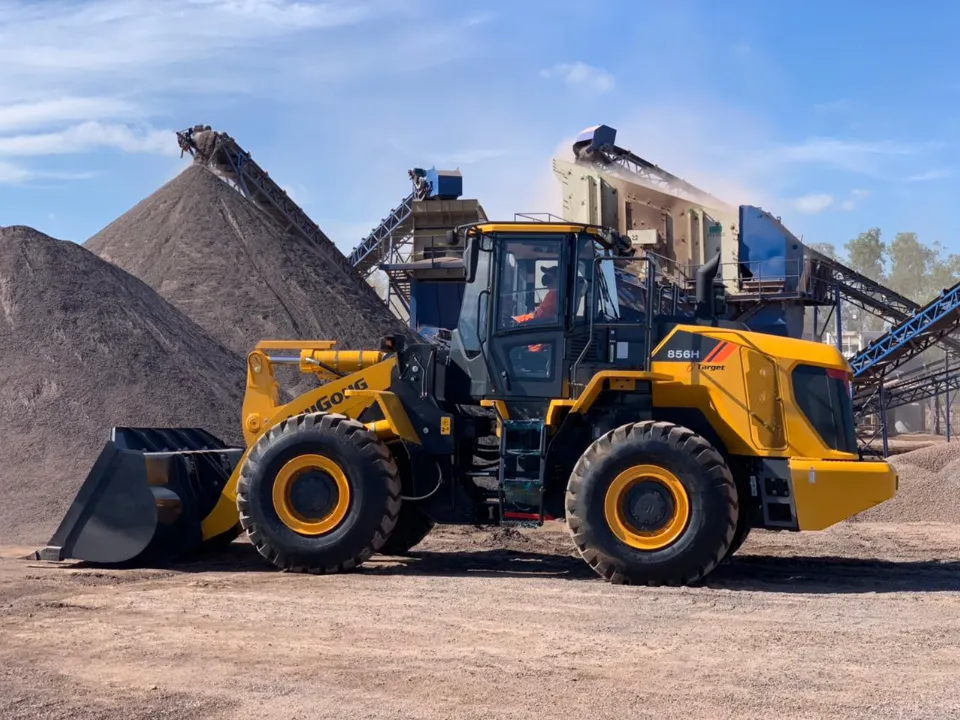 LiuGong 856H wheel loader in front of gravel stockpiles and conveyor belts at an aggregates yard