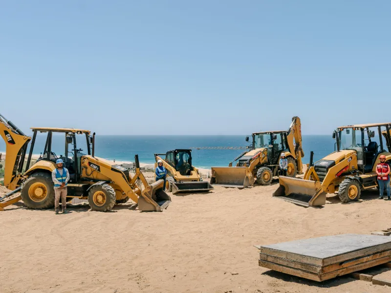 Retroexcavadoras CAT de la flotilla de renta de Creatio estacionadas sobre la playa en Los Cabos